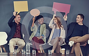 Letting their opinions be seen. a group of businesspeople holding up speech bubbles while waiting in line for an