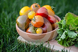 Lettuce, arugula leaves, tomatoes on a wooden plate