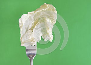 Lettuce leaf on a fork on a green background