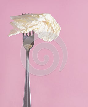 Lettuce leaf on a fork on a pink background