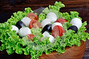Lettuce salad with mozzarella tomato and olive in a bowl