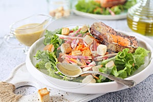 Lettuce salad with red fish, raw vegetables and croutons. Red fish sandwich with rye bread, poppy seeds and mustard sauce