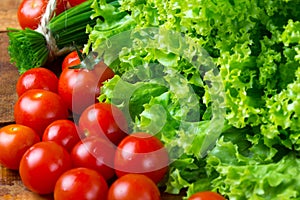 Lettuce salad, tomatoes and chives on wooden background.