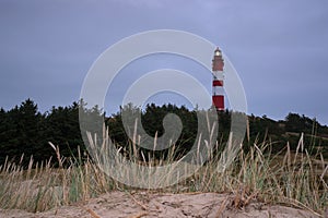 Leuchtturm Amrum lighthouse on a hill covered in the grass under a cloudy sky in Nebel, Germany