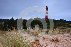 Leuchtturm Amrum lighthouse on a hill covered in the grass under a cloudy sky in Nebel, Germany