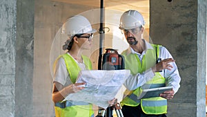 Leveling device and two construction specialists, builders, constructors standing near it and talking