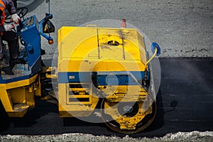 Leveling of new layer of asphalt by road roller.