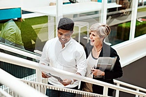 Levelling up together in business. Shot of two businesspeople walking up a staircase together in an office.