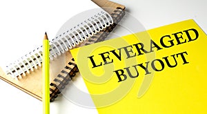 LEVERAGE BUYOUT text written on a yellow paper with notebook