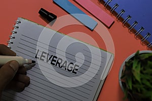 Leverage write on book. Isolated on pink table background