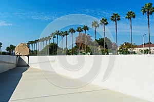 Levitated Mass art installation at the Los Angeles County Museum of Art. Empty trench visitors can walk through. Row of palm trees