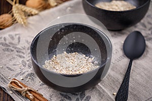 Levitating in a bowl of dry cereal oatmeal. Still-life on a wooden background.