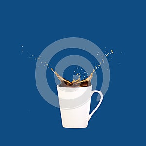 Levitating coffee mug with splashes on solid classic blue background. Coffee concept. Minimal art trend.