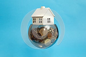 Levitating glass bowl full of coins with a small model house on top