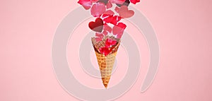 Levitating ice cream cone with splashes of rose petals and hearts. Surprise, holiday and coffee love concept. Minimal art trend.