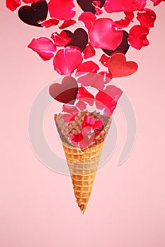 Levitating ice cream cone with splashes of rose petals and hearts. Surprise, holiday and coffee love concept. Minimal art trend.