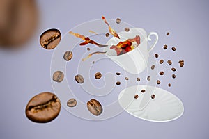Levitating white porcelain cup with splash of coffee from it and saucer surrounded by beans on gray-blue background