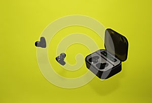 Levitation, black wireless Bluetooth headphones and charger - a container for headphones on a bright yellow background