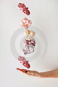 levitation of Colorful silk Scrunchies on woman hand isolated white. Hair tools and accessories.