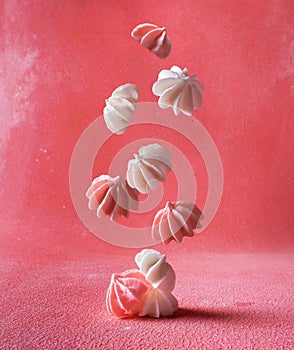 Levitation of delicate white and pink marshmallows on a pink background