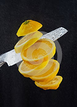 Levitation of freshly cut lemons. A knife cuts a lemon in the air. Flying slices of lemon isolated on a black background