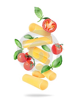 Levitation of italian cannelloni pasta tubes with tomatoes and basil leaves isolated on a white background