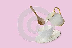 Levitation white coffee cup and saucer with milk pouring from a milk jug with a floating wooden spoon