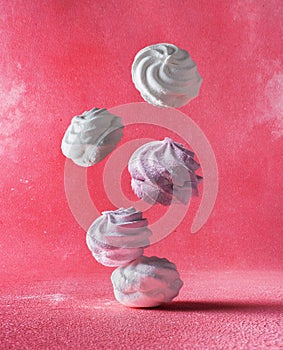 Levitation of white and pink round marshmallows close up on a pink background