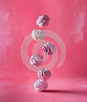 Levitation of white and pink round marshmallows on a pink background