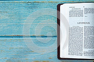 Leviticus open Holy Bible Book on a rustic wooden table with copy space