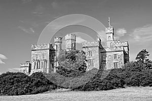 Lews Castle on blue sky in Stornoway, United Kingdom. Castle with green trees on natural landscape. Victorian style photo