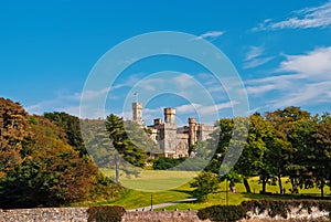 Lews Castle on estate landscape in Stornoway, United Kingdom. Castle with green grounds on blue sky. Victorian style photo