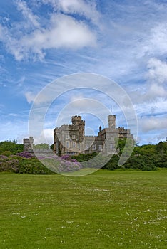 Lews Castle on the grassy slope above Stornoway Town and partially hidden by flowering Rhododendron trees photo