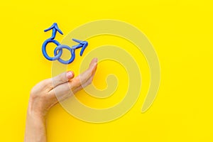 LGBT concept. Male Mars symbol in hands on yellow background top-down copy space