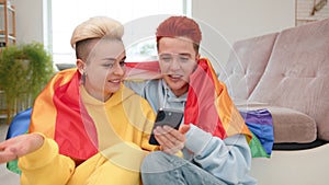 LGBT Couple in Rainbow Capes Sharing a Moment over Smartphone Screen