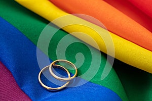 LGBT Gay marriage. Pair of golden rings on rainbow color textile, close up view. Copy space