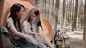 Lgbt lesbian women couple camping or picnic together in forest, teenager enjoy moment talking in front of their tent. Adventure