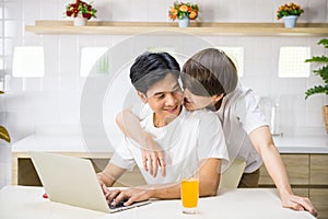 gay man kiss his partner working on laptop