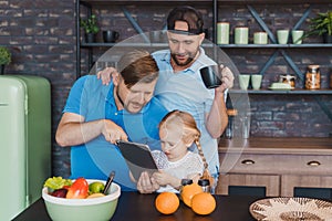 LGBT parents and their daughter using a tablet computer in the kitchen