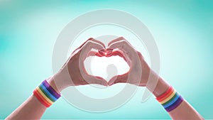 LGBT pride month with rainbow flag ribbon wristband on LGBTQ people heart-shape hands for International day against homophobia