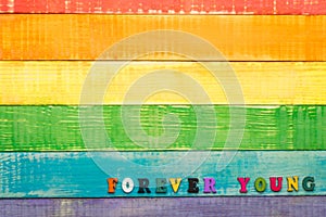 Lgbt rainbow colors wooden background with inscription forever young