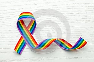 LGBT rainbow ribbon pride symbol. Stop homophobia. White wood background. Copy space for text.