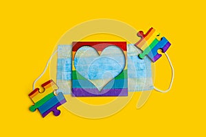 LGBT symbol puzzles and heart frame on a medical mask. Coronavirus quarantine, online festival and pride day 2020