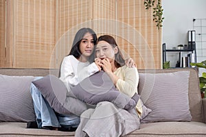 LGBT, Two beautiful scared girls watching horror movie at living room.