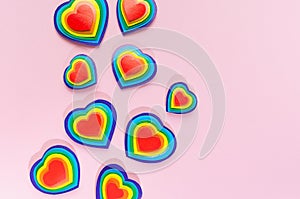 Lgbt Valentines day background - rainbow hearts as abstract border on pastel pink backdrop, top view.