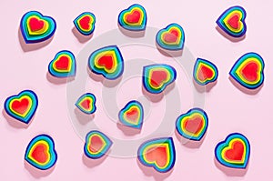 Lgbt Valentines day background - rainbow hearts as abstract pattern on pastel pink backdrop, top view.