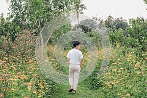 LGBT walking on pathway in spring beautiful yellow and orange cosmos flower field blooming in the garden