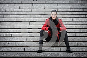 LGBTQ community lifestyle concept. Young homosexual man sits on a stairs. Handsome fashionable gay male model poses in