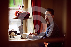 LGBTQ community lifestyle concept. Young homosexual man sits at the table in old-fashioned city cafe. Handsome gay male