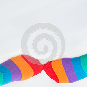LGBTQ+ community rights. Two left feet wearing multicolored rainbow flag socks, with white background